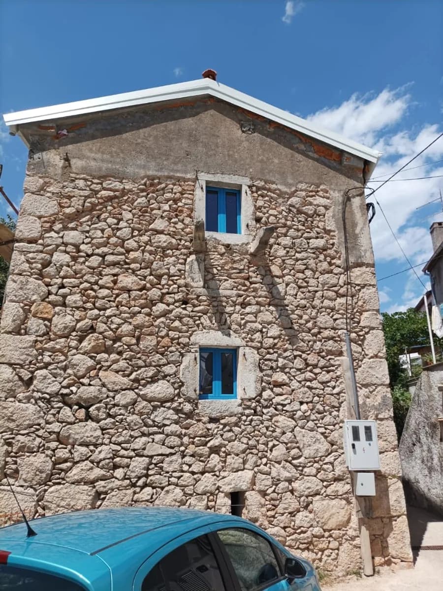 Kamena kuća s dva mala plava aluminijska prozora