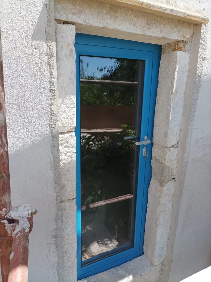 Plavi aluminijski prozor ugrađen u otvor u kamenom zidu