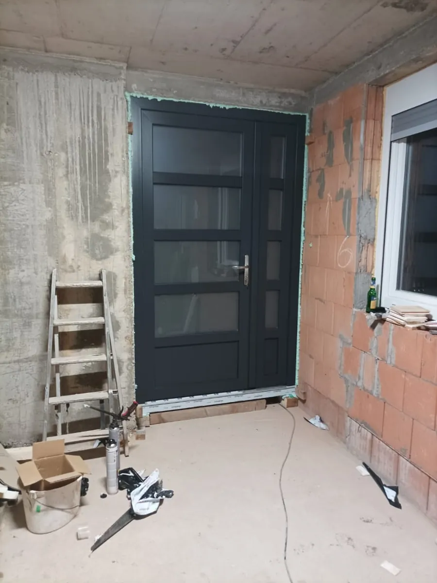 Antracitna ulazna vrata ugrađena u nedovršeni zid od blokova